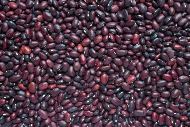 Unfocused red beans completely scattered in an even layer on a flat surface. Natural close-up background with space for copying - Photo, Image