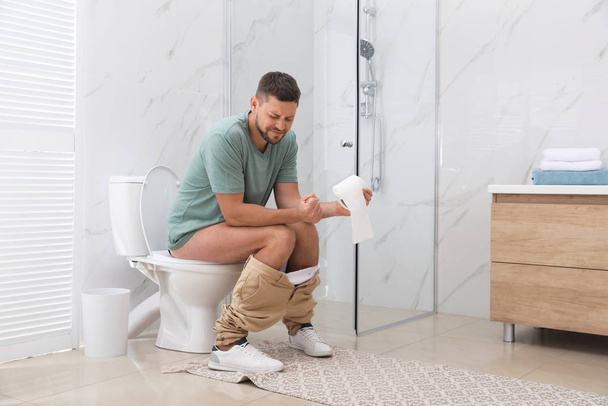 Man suffering from hemorrhoid on toilet bowl in rest room - Fotoğraf, Görsel