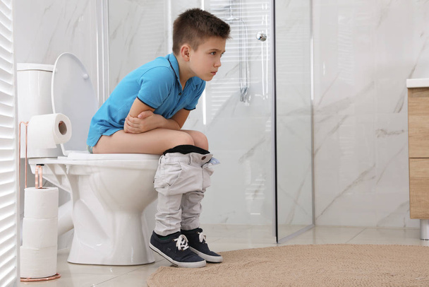 Boy suffering from hemorrhoid on toilet bowl in rest room - Фото, изображение