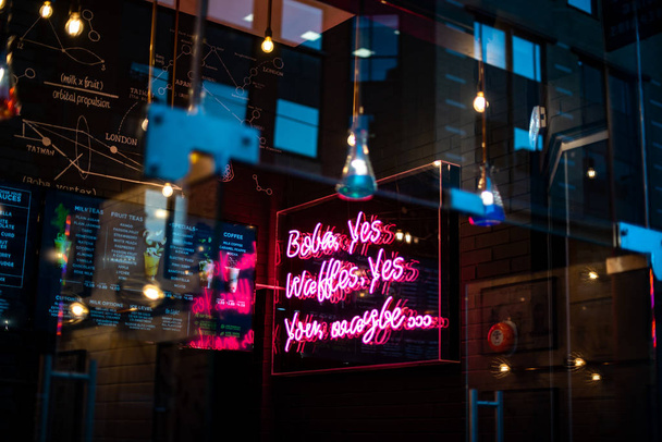 Nahaufnahme der neongeöffneten Reklame an der Außenseite eines kleinen Geschäfts mit Weihnachtsartikeln dunkelstädtischen blauen Laden - Foto, Bild