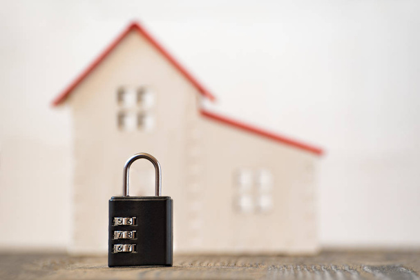 Συνδυασμός κλειδώματος και μοντέλου σπιτιού σε θολή φόντο. Αρχική και έννοια της ασφάλειας. - Φωτογραφία, εικόνα