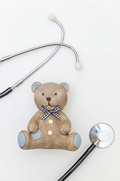 Wystarczy minimalny projekt zabawki niedźwiedź i sprzęt medyczny stetoskop izolowany na białym tle. Koncepcja lekarza opieki zdrowotnej. Symbol pediatry. Podkładka płaska, widok z góry - Zdjęcie, obraz