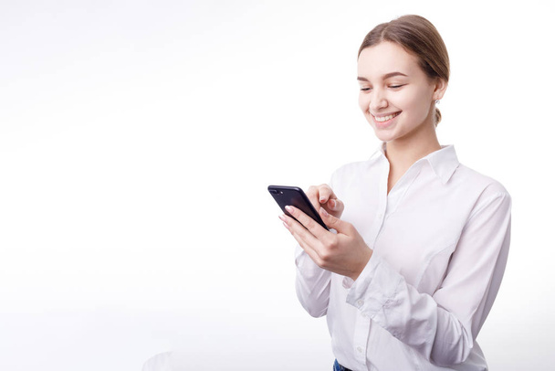 Glimlachende Enthousiaste zakenvrouw in witte blouse sms 'en - Foto, afbeelding