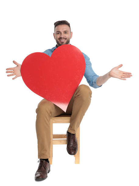 happy young casual man holding big red heart - 写真・画像