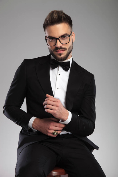 Tough groom adjusting his sleeve while wearing glasses - Foto, immagini