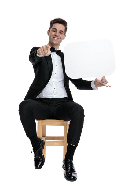 smiling young man holding speech bubble and pointing finger - Φωτογραφία, εικόνα