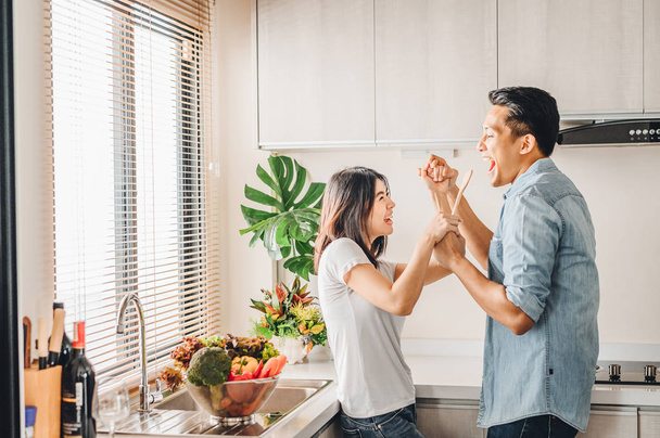 Aasialainen pari rakastunut laulaa ja tanssii yhdessä keittiössä
 - Valokuva, kuva
