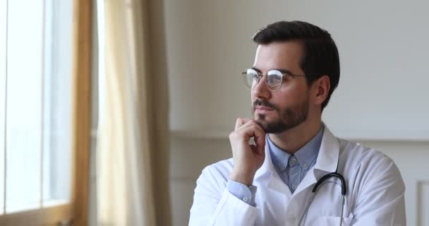 Successful thoughtful male professional doctor look through window dreaming thinking - Πλάνα, βίντεο