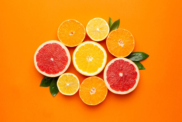 Citruses fruits on orange background, fruit flatlay, summer minimal compositon with grapefruit, lemon, mandarin and orange. Summer color , harvest, cutting fruits - Photo, image