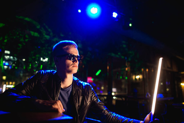 Handsome man in leather jacket with sunglasses testing LED light in night club neon lights - Zdjęcie, obraz