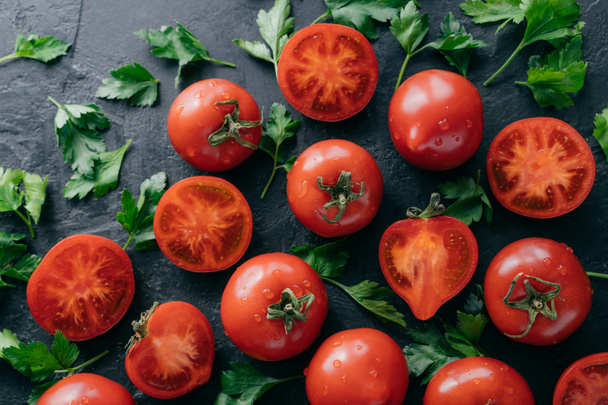 Φρέσκα χορτοφάγα σε σκοτεινό φόντο. Ώριμες κόκκινες ντομάτες και πράσινος μαϊντανό που συγκομίζονται από τον κήπο. Σταγόνες νερού σε βιολογικά προϊόντα. Νόστιμα προϊόντα για χορτοφάγους - Φωτογραφία, εικόνα