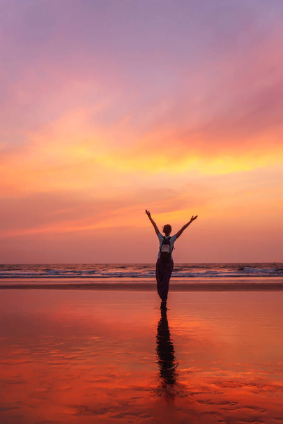 Nő felemelt kézzel érzi a szabadságot és élvezi Goa naplementét - Fotó, kép