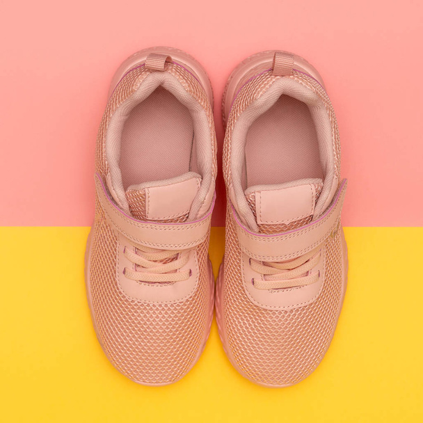 Розовые спортивные туфли на красочном фоне. Новые кроссовки на розовом и желтом пастельном фоне. Потеря веса и спортивная концепция. Вид сверху, плоский, квадратный формат instagram
 - Фото, изображение