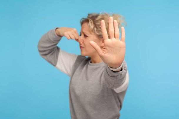 Bad breath. Woman in grey sweatshirt pinching nose with fingers, - Foto, Bild