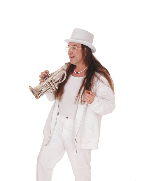 Un trompetista de pie con un traje blanco y sombrero
 - Foto, imagen
