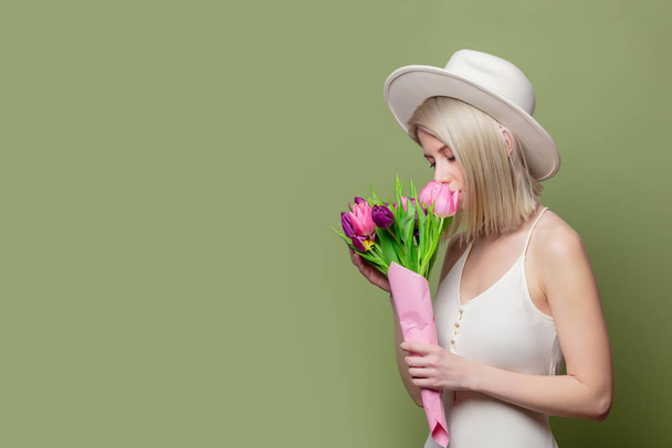 Beautiful blonde girl in white hat and dress with tulips - Foto, afbeelding