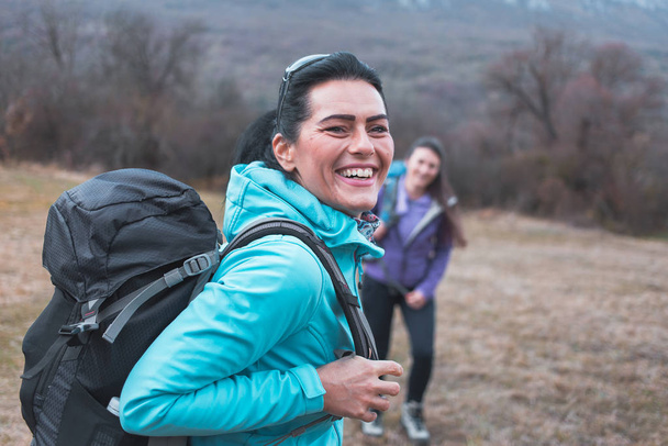 Cute female hiker in blue jacket, smiling, radiates happiness. - 写真・画像