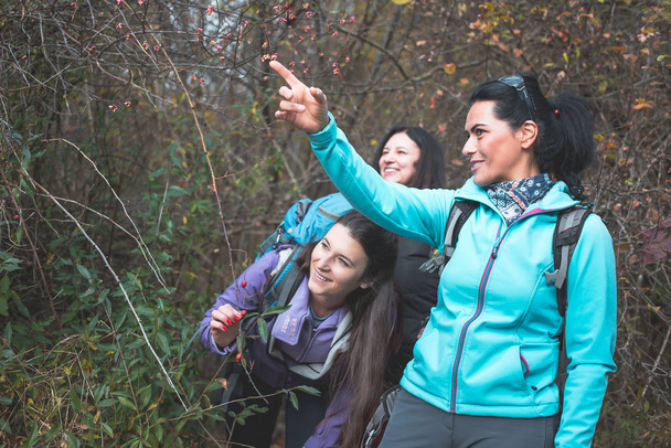 Girl hikers, woman in blue jacket as their guide, showing them where to go - Foto, Bild