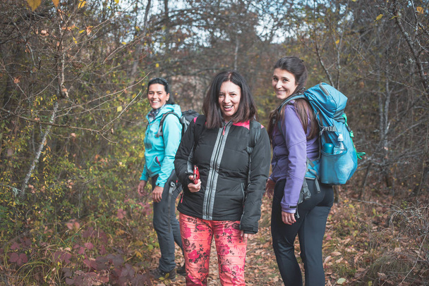 Három lány, túrázók, boldog és mosolygós pózol a fotón. Túrázás, hátizsák - Fotó, kép