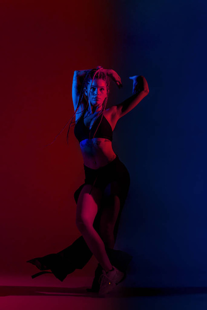 Μαύρη ντυμένη και πλεγμένη γυναίκα που χορεύει σε μπλε και κόκκινο - Φωτογραφία, εικόνα
