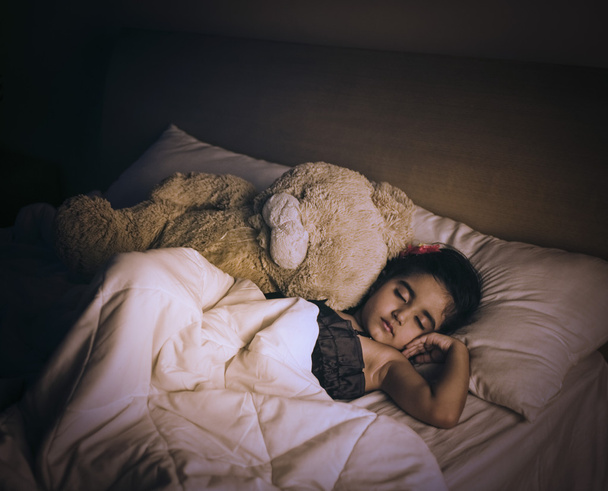 Девушка спит на кровати с плюшевым мишкой
 - Фото, изображение