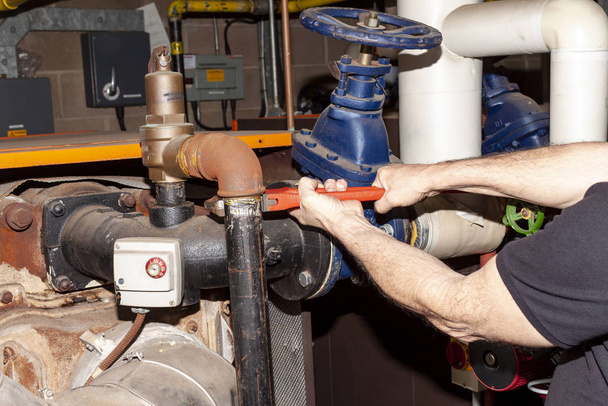 Ingeniero de calderas retirando un tubo de una válvula de seguridad
 - Foto, imagen
