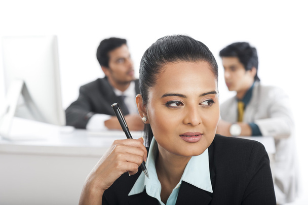 Крупный план предпринимательницы, держащей ручку со своими коллегами на заднем плане
 - Фото, изображение