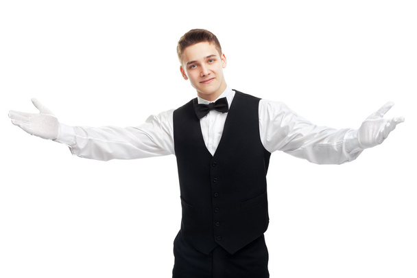 Young smiling waiter opens his arms in welcome - Valokuva, kuva