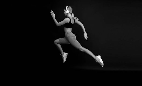 Run hard to get into shape. Woman run black background. Jogger jump with long run. Fit athlete in fashion sportswear. Athletic female sprinter or runner. Active and dynamic. Run fast, finish soon - Foto, afbeelding