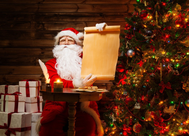 Santa claus v dřevěných domů vnitřní hospodářství prázdný seznam přání svitek - Fotografie, Obrázek