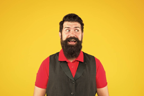 Happy face. Hospitality staff. Restaurant cafe staff wanted. Man bearded hipster with mustache wear vest shirt uniform yellow background. Shop staff concept. Salesman career. Hiring shop store worker - Foto, Imagen