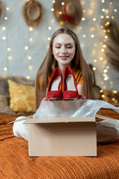 Mujer joven adulta desempacando caja de cartón en casa
 - Foto, imagen