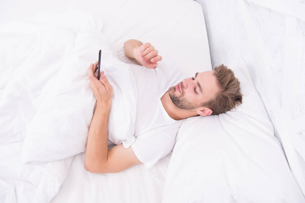 man use smartphone from the early morning. whole world in phone. he is blogging. flirting and sending text message. internet addiction and mobile abuse concept. man in bed chatting - Foto, afbeelding