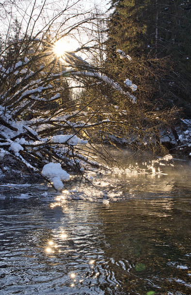 Estallido de sol en invierno con el río fluyendo
 - Foto, imagen