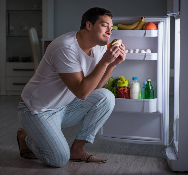 Man at the fridge eating at night - Photo, Image