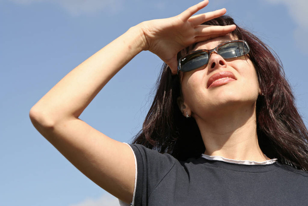 young woman in sunglasses against blue sky - Fotó, kép