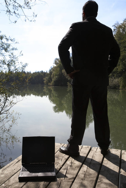 man with laptop on the bank of the lake - Foto, Imagen