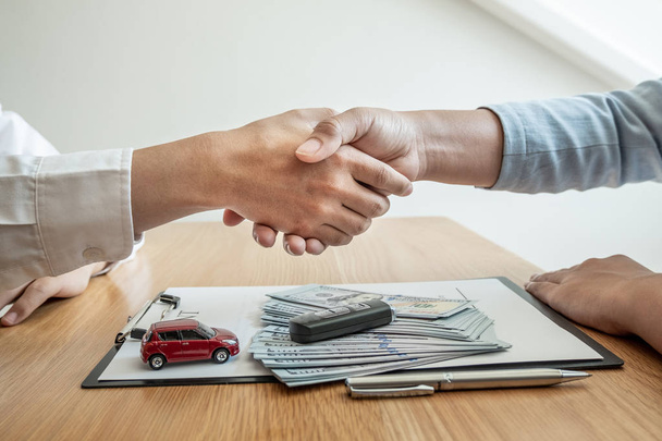 Händeschütteln, Autohaus berät über Versicherungsdetails und Mietwageninformationen und übergibt die Schlüssel nach Unterzeichnung des Mietvertrages - Foto, Bild