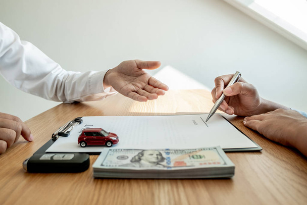 Car dealership provides advice about insurance details and car rental information and delivers the keys after signing the rental contract - Photo, Image