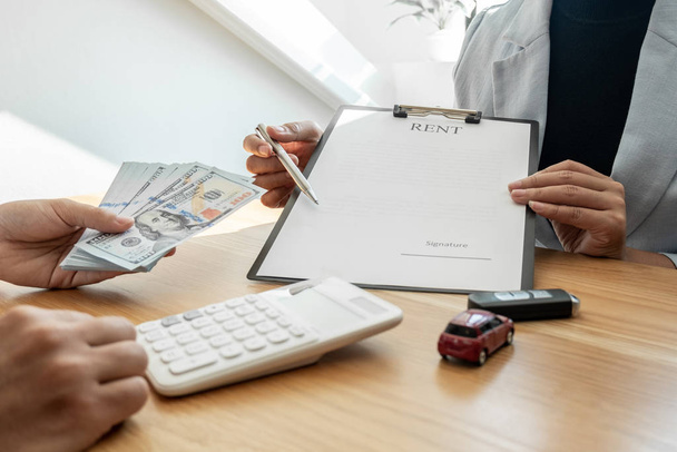 Autohaus berät über Versicherungsdetails und Mietwageninformationen und übergibt die Schlüssel nach Unterzeichnung des Mietvertrages - Foto, Bild