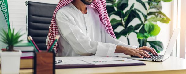 ラップトップコンピュータで作業しているアラビア人のビジネスマン。 - 写真・画像
