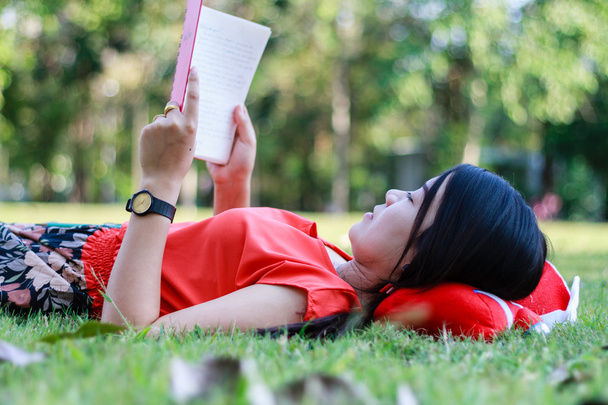 Beautiful young woman-student reading book on grass - Фото, изображение