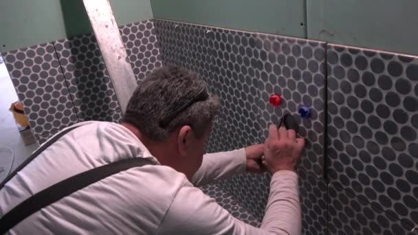 Kvalifikovaný pracovník dělat značky na dlaždice zvětšit díry kolem vodovodní trubky - Záběry, video