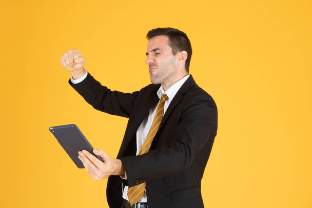 Portrait d'homme d'affaires joyeux utilisant la tablette sur fond jaune
 - Photo, image