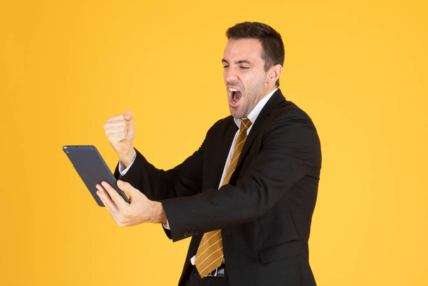 Портрет жизнерадостного бизнесмена с помощью планшета на желтой бэкгро
 - Фото, изображение