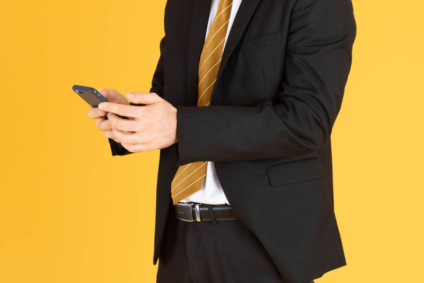 Porträt eines selbstbewussten Geschäftsmannes mit Smartphone auf gelbem Grund - Foto, Bild