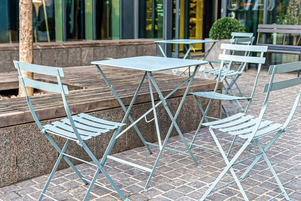 Klappstühle und Tische aus Metall in einem Straßencafé - Foto, Bild
