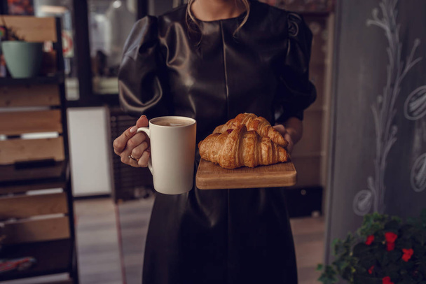 クローズアップ女性手サービスホットラテとクロワッサンでコーヒーs - 写真・画像