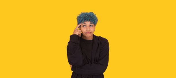 young african american girl or woman with blue hair isolated on yellow background - Фото, зображення