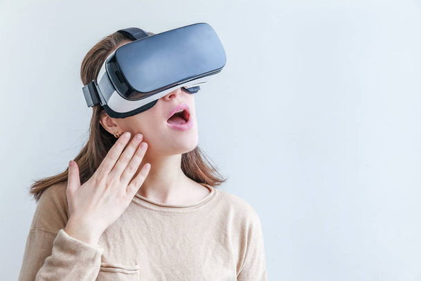 Hymyile nuori nainen yllään käyttäen virtuaalitodellisuus VR lasit kypärä kuulokkeet valkoisella taustalla. Älypuhelin käyttäen virtuaalitodellisuus suojalasit. Teknologia, simulointi, hi-tech, videopeli käsite. - Valokuva, kuva